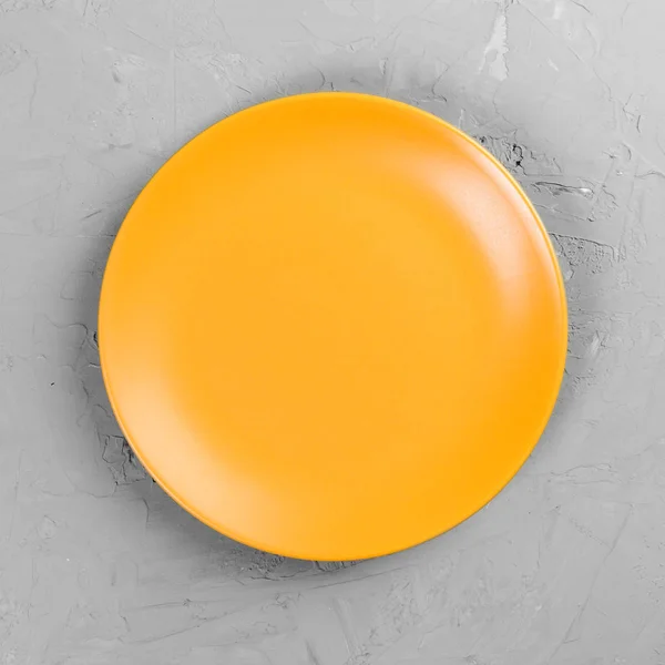 Placa redonda amarilla sobre fondo de mesa de cemento gris. Vista superior, plantilla para su diseño —  Fotos de Stock