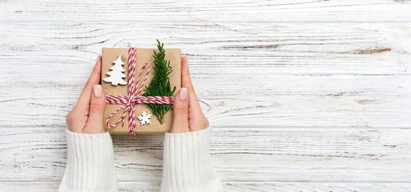 Woman hands give wrapped christmas handmade present in paper top view banner . Copy space