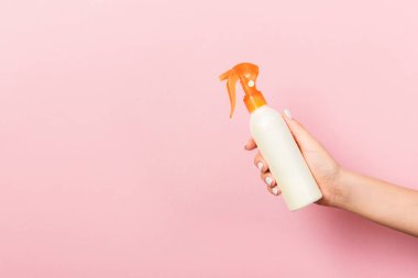 Kadın el losyon izole sprey krem şişe tutarak. Kız pembe arka plan üzerinde kozmetik ürünler vermek