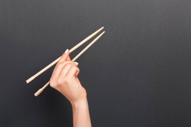 Siyah arka plan üzerinde kadın elinde ahşap çubukları yaratıcı görüntü. Kopya alanı ile Japon ve Çin gıda