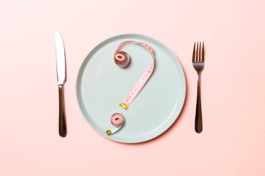 Pembe arka planda yuvarlak plaka üzerindeki şeritten yapılmış soru işareti. Tereddüt ve diyet konseptinin üst görüşü