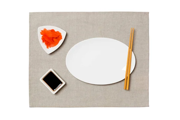 Tom oval vit tallrik med ätpinnar för sushi, ingefära och sojasås på grå servett bakgrund. Toppvy med kopierings utrymme för dig design — Stockfoto