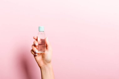 Kadın el tutarak krem şişe losyon izole. Kız pembe arka plan üzerinde tüp kozmetik ürünleri vermek