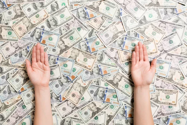 Çeşitli dolar arkaplanındaki kadın eli manzarası. Tasarımınız için boş alanı olan zenginlik kavramı. Para dilenmek.
