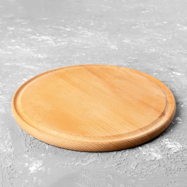 Порожня кругла дерев'яна тарілка на текстурованому столі. Дерев'яна тарілка для їжі або овочів, що подаються клієнтам — стокове фото