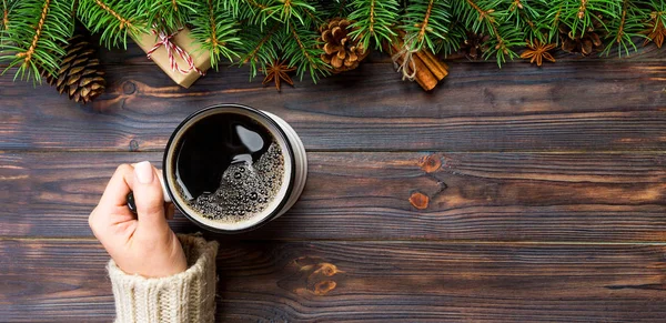 Frau Hand halten Tasse Kaffee auf schwarzem Holz Weihnachten Hintergrund. Banner von oben, Kopierraum — Stockfoto