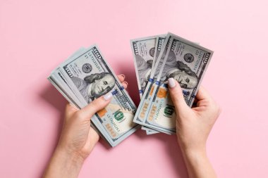 Para sayan kadın ellerinin en iyi görünümü. Renkli arka planda 100 dolarlık banknotlar. Maaş kavramı. Rüşvet kavramı