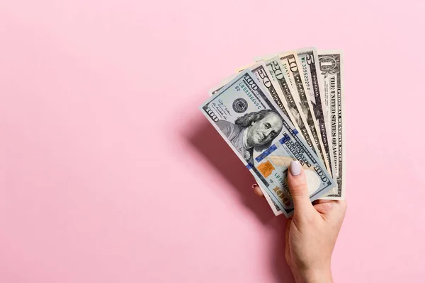 Pohled na samičí ruce, které drží na barevném pozadí vějíř s penězi. Různé dolarové bankovky. Koncept úvěru a zadlužení s prostorem pro kopírování — Stock fotografie