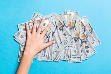 Kadın el renkli arka plan üzerinde yüz dolarlık banknotlar yığını üzerinde yalan. Para tasarrufu ve refah kavramı