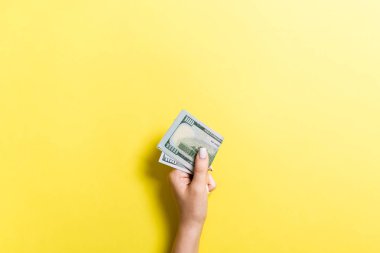 Renkli arka planda bir paket para tutan kadın elin üst görünümü. Yüz dolar. Tasarım için boş alan ile Iş konsepti. Sadaka ve ipuçları kavramı