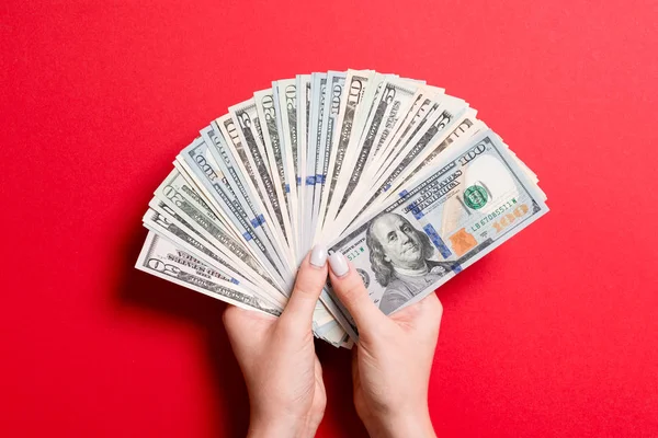 Vista superior de la mano femenina sosteniendo un ventilador del dinero en fondo colorido. Varios billetes de dólar. Concepto de crédito y deuda — Foto de Stock