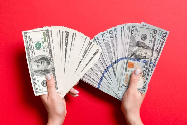 Fan of new one hundred dollar bills in one female hand and old one hundred dollar bills in another hand on colorful background. Investment concept