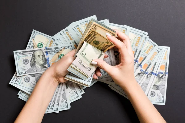 İş kadını elleri renkli arka planda yüz, beş ve diğer dolar banknotları sayar. Maaş ve ücret kavramı. Yatırım kavramına en üst düzey bakış