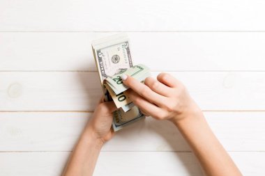 Bir iş kadınının elleri ahşap arka planda farklı dolar banknotları sayıyor. Başarı ve zenginlik kavramı