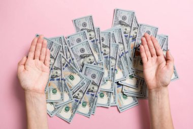 Kadın elleri renkli arka plan üzerinde yüz dolarlık banknotlar yığını üzerinde yalan. Para tasarrufu ve refah kavramı