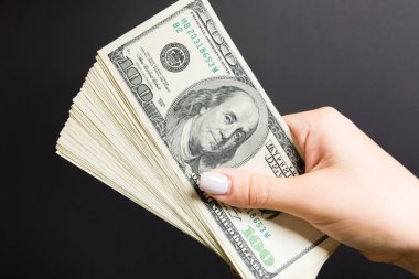 Renkli arka planda yüz dolar bir fan tutan kadın el üst görünümü. Kredi konsepti. Refah kavramı