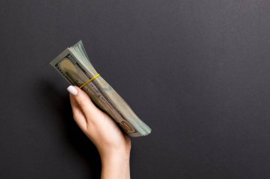 Renkli arka planda kadın elinde yüz dolarlık banknotlar demeti. Kopyalama alanı ile finans ve iş kavramı