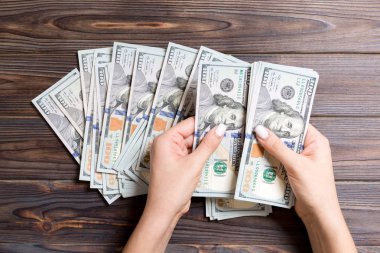 İş kadınının elleri renkli arka planda 100 dolarlık banknotları sayıyor. Maaş ve ücret kavramı. Yatırım kavramına en üst düzey bakış