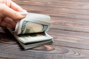 Ahşap arka planda yüz dolarlık banknotlar sayan bir iş kadınının ellerine bakış açısı. Başarı ve zenginlik kavramı