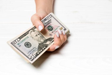 Kadın el ahşap arka plan üzerinde para bir demet tutan. Elli ve diğer dolar banknotların perspektif görünümü. Tasarım için boş alan ile Maaş kavramı