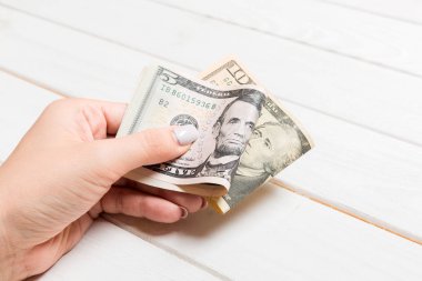 Ahşap arka planda kadın elinde beş ve on dolarlık banknotlar. Kopya alanı ile maaş kavramı