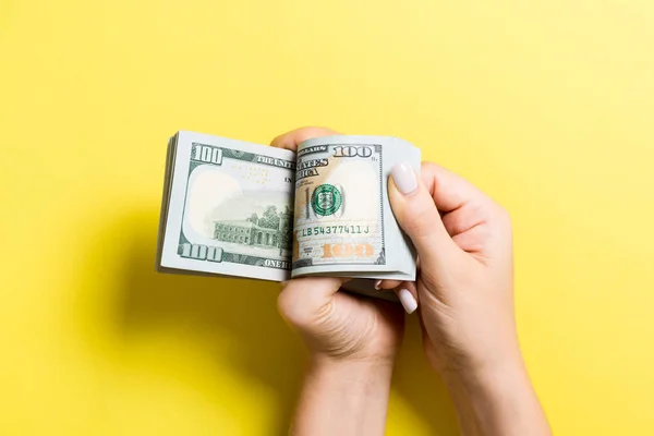 Pohled na ruku businessovy ženy počítá 100 dolarových bankovek na barevném pozadí. Koncepce úspěchu a bohatství — Stock fotografie