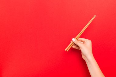 Kırmızı arka plan üzerinde çubukları tutan kadın el Kırpma görüntüsü. Kopya alanı ile Japon gıda kavramı