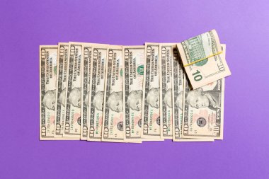 Renkli arka plan üzerinde bir satırda yalan 10 dolarlık banknotlar üst görünümü. Para tasarrufu konseptinin kapatılması