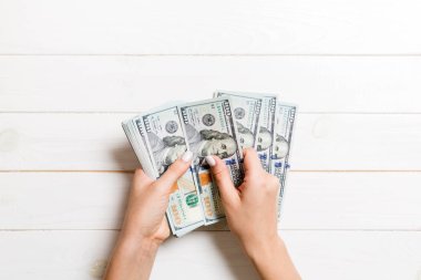 Kadın eli para sayıyor. Ahşap arka planda 100 dolarlık banknotlar. İş konsepti