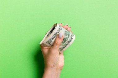 A pack of one hundred dollar bills in female hand on colorful background. Salary concept