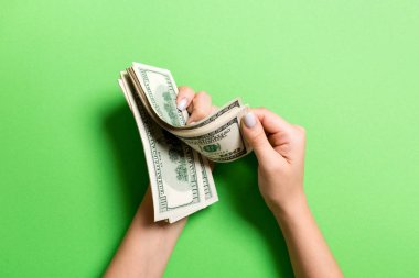 İş kadınının elleri renkli arka planda 100 dolarlık banknotları sayıyor. Maaş ve ücret kavramı. Yatırım kavramına en üst düzey bakış