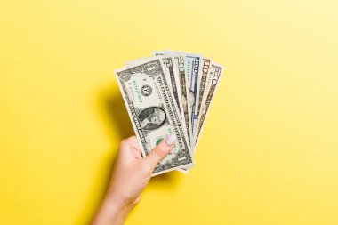 Renkli arka planda çeşitli dolar banknotları veren kadın elin üst görünümü. Sadaka ve bağış konsepti