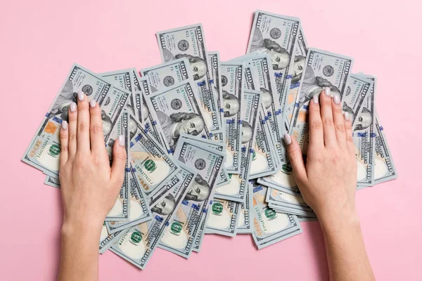 100 dolarlık banknotyığının üzerinde yatan kadın ellerinin en iyi görüntüsü. Renkli arka planda başarı ve zenginlik kavramı