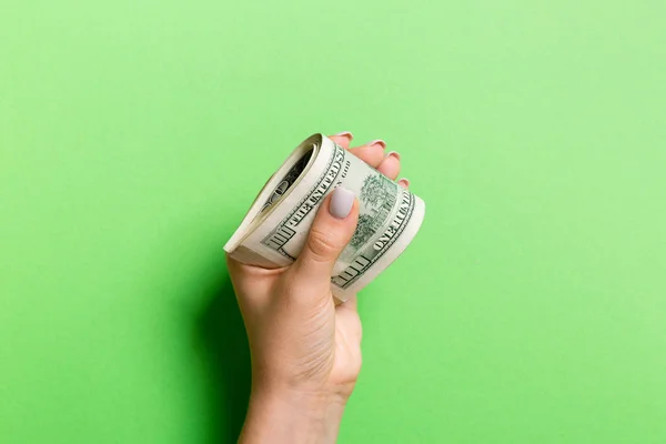 Un paquete de billetes de cien dólares en mano femenina sobre un fondo colorido. Concepto salarial — Foto de Stock