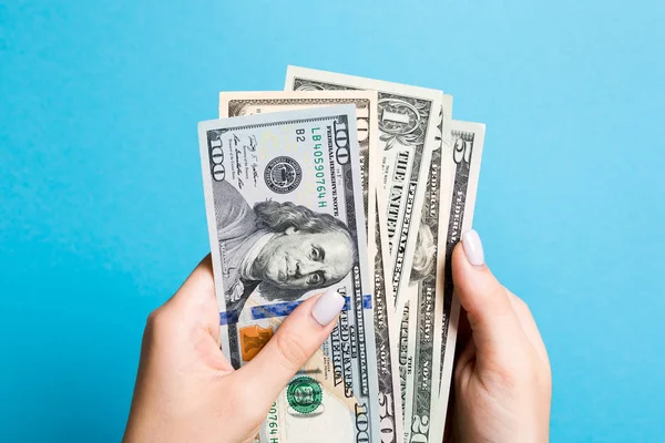 Vista superior de la mano femenina sosteniendo un paquete de varios billetes de dólar sobre fondo colorido. Concepto salarial y salarial — Foto de Stock