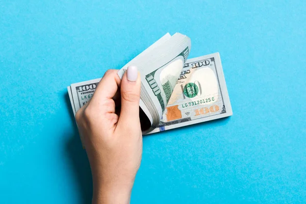 Bovenaanzicht van de handen van een zakenvrouw tellen 100 dollar bankbiljetten op kleurrijke achtergrond. Succes-en vermogens concept met Kopieer ruimte — Stockfoto