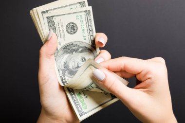 Para sayan kadın ellerinin en iyi görünümü. Renkli arka planda 100 dolarlık banknotlar. Maaş kavramı. Rüşvet kavramı
