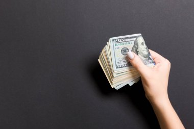 Top view of female hand holding a pack of money on colorful background. Various dollars. Business concept with empty space for your design. Charity and tips concept