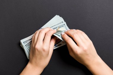 Renkli arka planda yüz dolarlık banknotlar sayan bir iş kadınının ellerinin en iyi görünümü. Başarı ve zenginlik kavramı