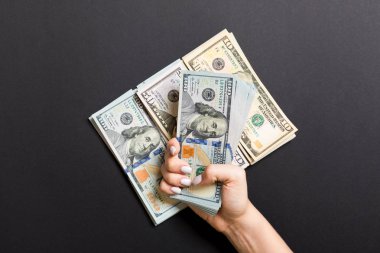 Kadın el renkli arka plan üzerinde çeşitli dolar banknotları yığını üzerinde yalan. Para tasarrufu ve refah kavramı