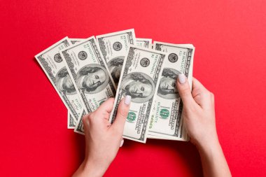 Para sayan kadın ellerinin en iyi görünümü. Renkli arka planda 100 dolarlık banknotlar. Maaş kavramı. Rüşvet kavramı