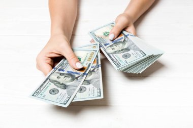 Kadın el ahşap arka plan üzerinde yüz dolarlık banknotlar veriyor. Zenginlik kavramına bakış açısı
