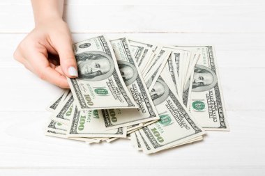 İş kadınının elleri ahşap zeminde 100 dolarlık banknotları sayıyor. Maaş ve ücret kavramı. Yatırım kavramına en üst düzey bakış