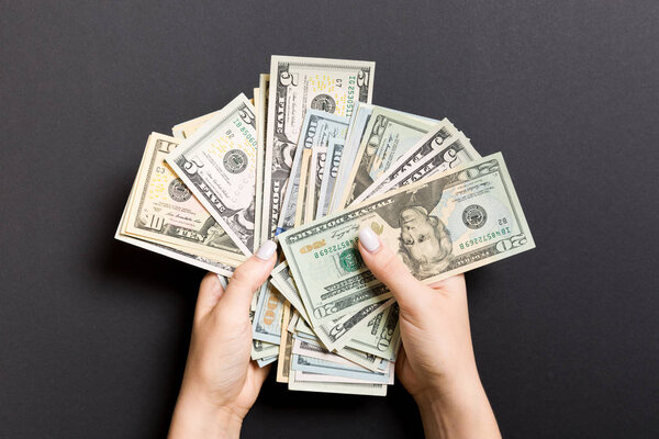 Вид сверху различных долларовых банкнот в женских руках на цветном фоне. Бизнес и финансовая концепция
