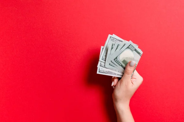 Un paquete de billetes de cien dólares en mano femenina sobre un fondo colorido. Concepto salarial con espacio de copia — Foto de Stock