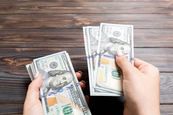 Vrouwelijke hand geven 100 dollar bankbiljetten op houten achtergrond. Perspectief van het vermogens concept — Stockfoto