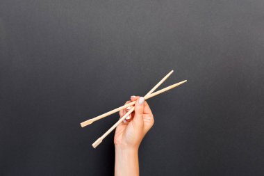 Kadın el siyah arka plan üzerinde çubukları tutarak. Fikriniz için boş alan ile Suşi kavramı