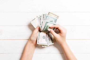 İş kadınının elleri tahtadan arka planda yüz dolarlık banknotları sayıyor. Maaş ve maaş kavramı. Yatırım konseptinin en üst görünümü