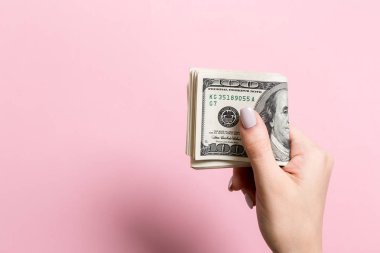 Renkli arka planda bir paket para tutan kadın elin üst görünümü. Yüz dolar. Tasarım için boş alan ile Iş konsepti. Sadaka ve ipuçları kavramı