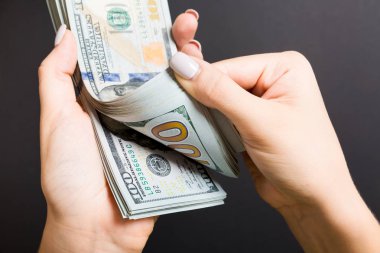Para sayan kadın ellerinin en iyi görünümü. Renkli arka planda 100 dolarlık banknotlar. Maaş kavramı. Rüşvet kavramı
